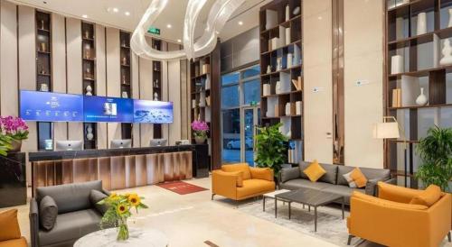a lobby with couches and chairs in a building at VX Hotel Wuxi Xinwu District Executive Center Wanda Plaza in Wuxi
