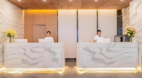 two women sitting at a counter with their laptops at VX Hotel Xiamen Siming District Xiamen University Huandao Road in Xiamen