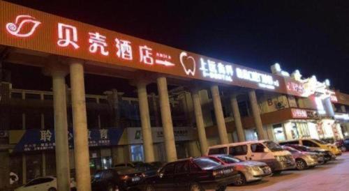 a parking lot with cars parked in front of a building at Shell Hotel Shanghai Jinshan Wanda Plaza in Nanhui