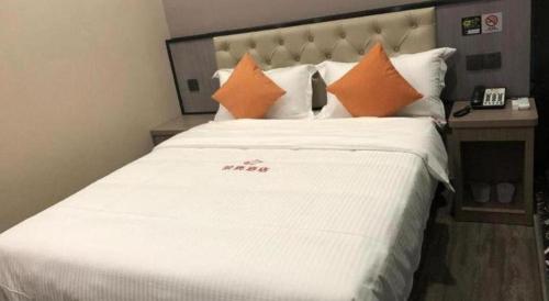 a large white bed with orange pillows in a room at Shell Hotel Shanghai Jinshan Wanda Plaza in Nanhui