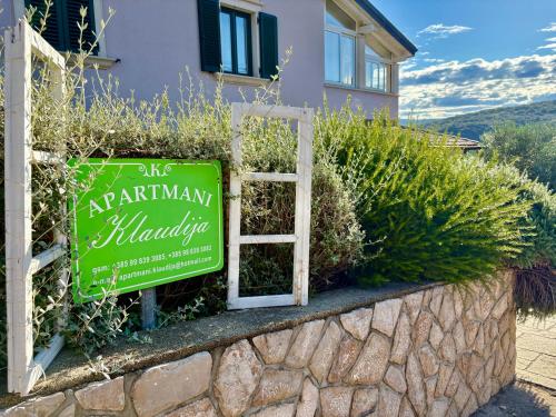 a green sign in front of a building at Apartmani Klaudija in Valun