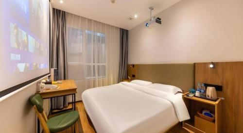 a bedroom with a large white bed and a desk at GreenTree Inn Express Lanzhou West Passenger Station Lanzhou Center in Lanzhou