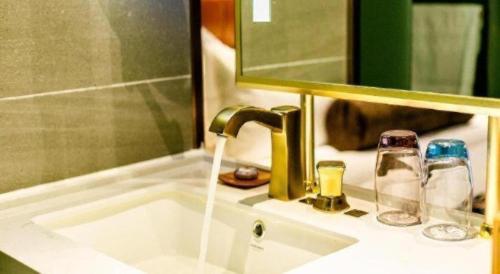 a bathroom sink with a faucet with water coming out at James Joyce Coffetel· Xianyang Renmin Road Central Square Store in Xianyang