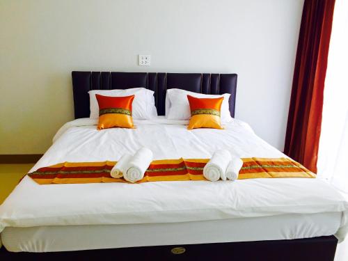a bed with orange pillows and white towels on it at Retro Twin Home @Maesot in Mae Sot