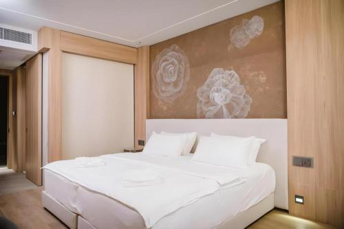 a bedroom with a white bed with a painting on the wall at Riverton Hotel in Samut Songkhram