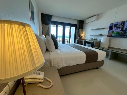 a bedroom with a bed with a lamp and a phone at Siam Triangle Hotel Chiang Sean in Chiang Saen