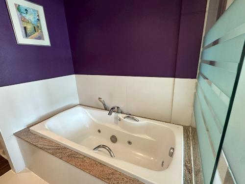 a white tub in a bathroom with purple walls at Siam Triangle Hotel Chiang Sean in Chiang Saen