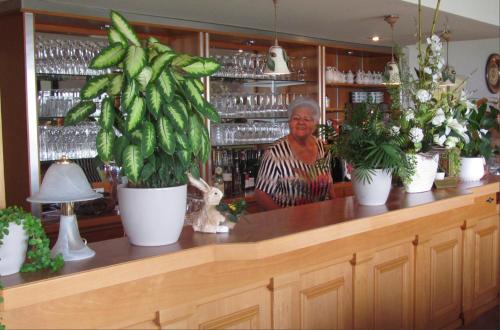 une femme debout derrière un comptoir avec des plantes en pot dans l'établissement Hotel Rheinkrone, à Coblence