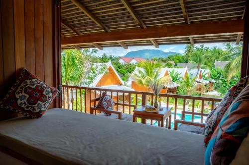 a room with a bed and a balcony with a view at The Jam Boutique Hotel in Luang Prabang
