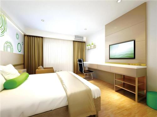 ein Hotelzimmer mit einem Bett, einem Schreibtisch und einem Fernseher in der Unterkunft GreenTree Inn Express Yingtan Yujiang Railway Station in Yingtan