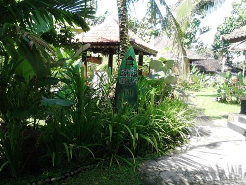 a sign in a garden in front of a house at Pondok Balian in Selemadeg