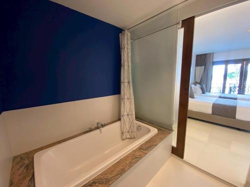 a bathroom with a tub and a bedroom with a bed at Siam Triangle Hotel Chiang Sean in Chiang Saen