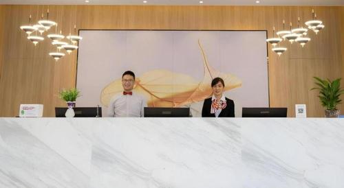 two people are standing behind a large white table at Green Tree Inn Express Fuzhou Three Lanes and Seven Alleys Nanmendou Metro Station in Fuzhou