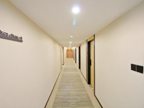 a hallway with white walls and a long aisle at GreenTree Inn Express Zhangjiagang Hexing Town Shazhou Professional Institue of Technology in Qiwei