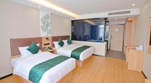 a hotel room with two beds and a bathroom at GreenTree Inn Express Zhangjiagang Hexing Town Shazhou Professional Institue of Technology in Qiwei