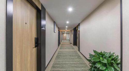 a hallway with a long aisle with plants in a building at GreenTree Inn Express Zhangjiagang Hexing Town Shazhou Professional Institue of Technology in Qiwei