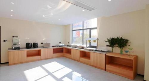 a large kitchen with wooden counters and a window at GreenTree Inn Express Zhangjiagang Hexing Town Shazhou Professional Institue of Technology in Qiwei