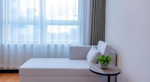 a white couch with a plant on a table in front of a window at GreenTree Inn Express Hebei Tangshan Guyan District Xinguang Road in Tangshan