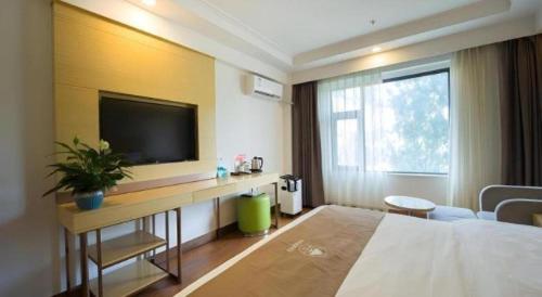 a hotel room with a bed and a flat screen tv at Green Tree Inn Tibet Lhasa Zhaji Temple in Lhasa