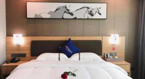 a bedroom with a bed with two horses on the wall at Jun Hotel Guangdong Zhanjiang Xiashan South Railway Station in Zhanjiang