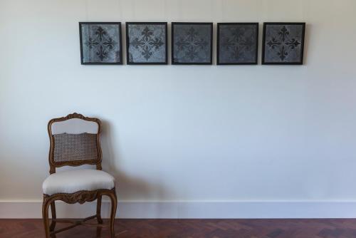 a chair sitting in front of a wall with four pictures at República Bed & Breakfast in Lisbon