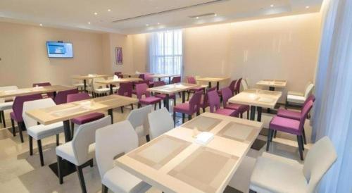a dining room with tables and purple chairs at Lavande Hotel Huizhou Shiwan in Huizhou