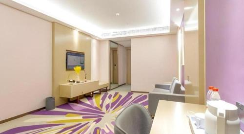 a room with a desk and chairs and a tv at Lavande Hotel Huizhou Shiwan in Huizhou