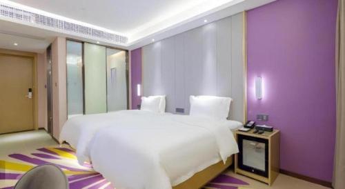 a bedroom with a large white bed and purple walls at Lavande Hotel Huizhou Shiwan in Huizhou