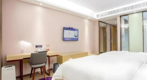 a bedroom with a bed and a desk and a tv on the wall at Lavande Hotel Huizhou Shiwan in Huizhou