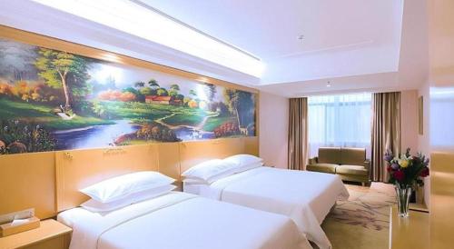 a hotel room with two beds and a painting on the wall at Vienna Hotel Hubei Xiangyang Tang City Gulou in Xiangyang