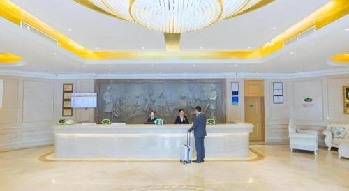 a man standing in a lobby with a luggage at Vienna Hotel Hubei Xiangyang Tang City Gulou in Xiangyang