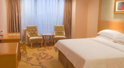 a hotel room with a bed and two chairs at Vienna Hotel Guangxi Guilin Xing'an in Guilin
