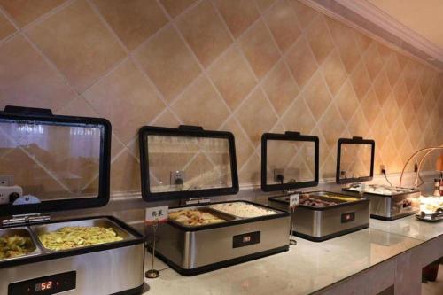 a buffet with several trays of food on a counter at Vienna Hotel Inner Mongolia Tongliao Development Zone in Tongliao