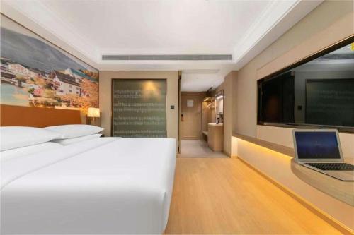 a bedroom with a bed and a laptop on a wall at Vienna Hotel Hubei Jinzhou Changjiang University in Caoshi