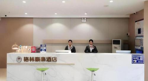 two women sitting at a counter in a restaurant at Green Tree Inn Luoyang Fenghuang Mansion Mudan Square Metro Station in Luoyang