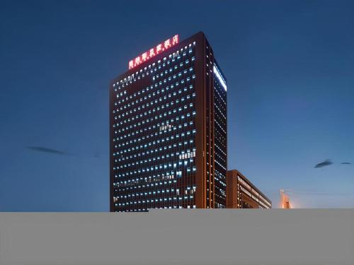 a tall building with a sign on top of it at Venus Royal Hotel Nanning East High-Speed Railway Station in Nanning