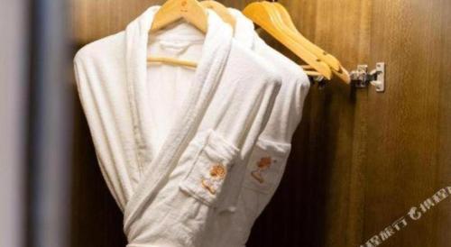a white robe is hanging on a door at Venus Royal Hotel Nanning East High-Speed Railway Station in Nanning