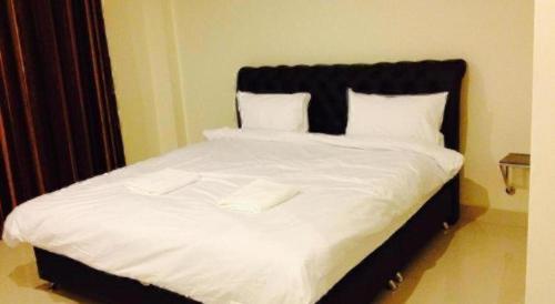 a bed with white sheets and two white towels on it at Niwtara Place Lom Sak Hotel in Phetchabun