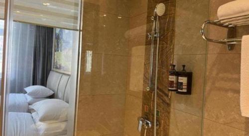 a bathroom with a shower and a bed with white pillows at Vienna Hotel Zhejiang Lishui Qingtian Post Building in Lishui