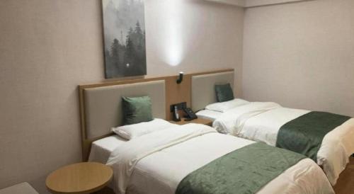 a hotel room with two beds and a table at GreenTree Inn Luoyang Henan University of Science and Technology in Luoyang