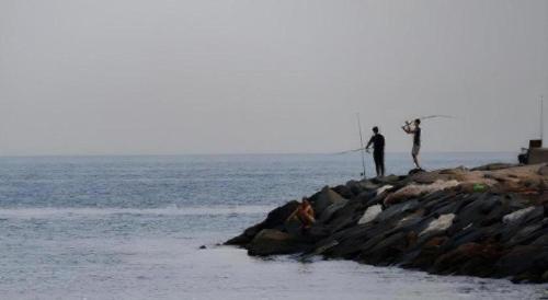 two people are standing on the rocks near the ocean at Lotus Furnished Hotel Apartments LLC. Ajman in Ajman 