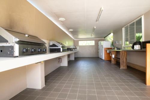 Una cocina grande con un largo pasillo con electrodomésticos. en Tropical Hibiscus Caravan Park, en Mission Beach