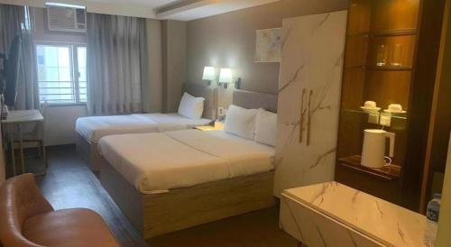 a hotel room with two beds and a chair at Sunny Day Hotel in Hong Kong