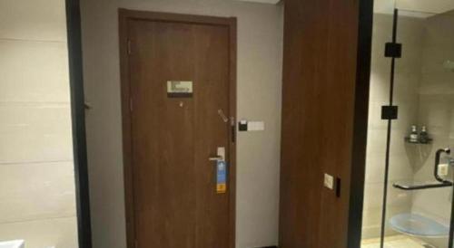 a wooden door in a room with a bathroom at JTOUR Inn Wuhan Textile University in Wuhan