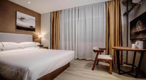 a bedroom with a bed and a chair and a desk at JTOUR Inn Wuhan Textile University in Wuhan