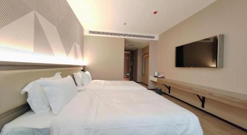 a bedroom with a large white bed with a flat screen tv at Borrman Hotel Korla Peacock River in Korla
