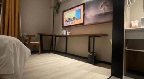 a room with a desk and a tv on the wall at JTOUR Inn Wuhan Textile University in Wuhan