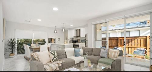 a living room with a couch and a kitchen at Brand new 5 star category home at RedHead beach in Redhead