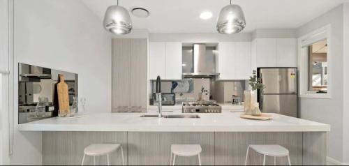 eine Küche mit einer Theke mit Hockern in der Unterkunft Brand new 5 star category home at RedHead beach in Redhead