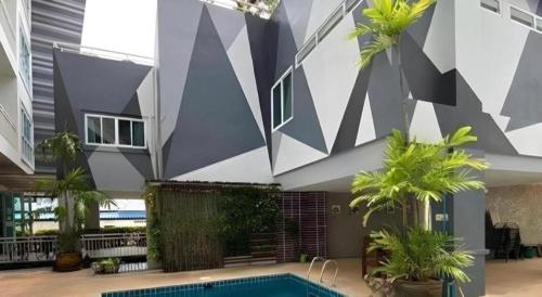 a building with a swimming pool and palm trees at The Grace Residence in Surin